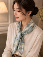 Model wearing Camellia Mist Blue 50 cm silk scarf with gold-tone pearl drop earrings